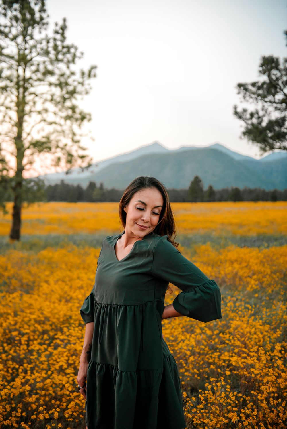 Candid shots of a woman dancing in a green dress among yellow wildflowers at sunset.