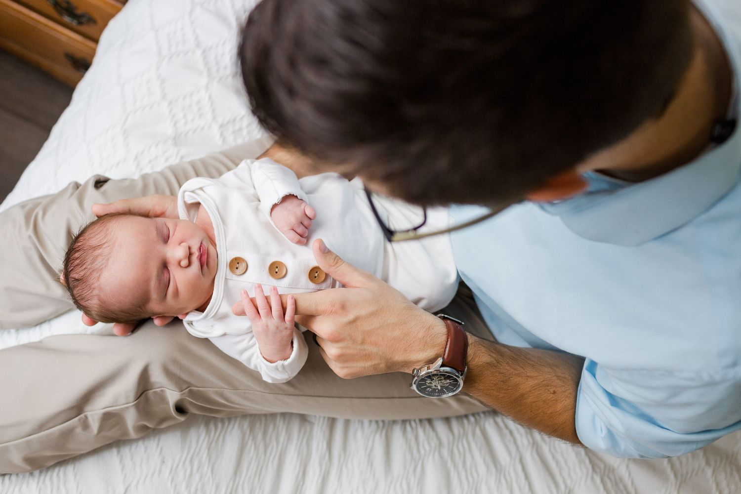 Baby lying on bed for a newborn photo session with soft lighting.
