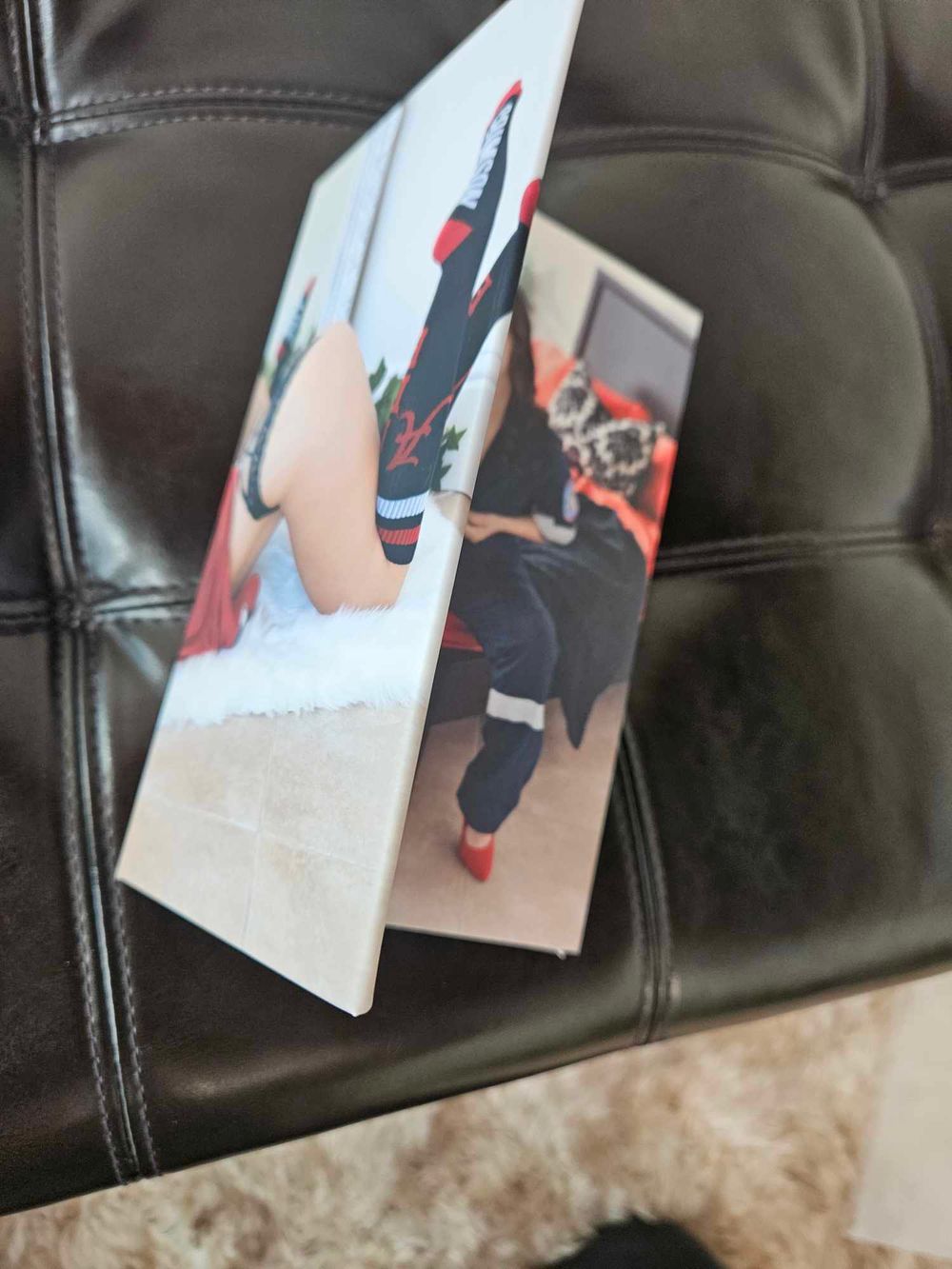 Folded photo prints arranged on dark leather upholstery.