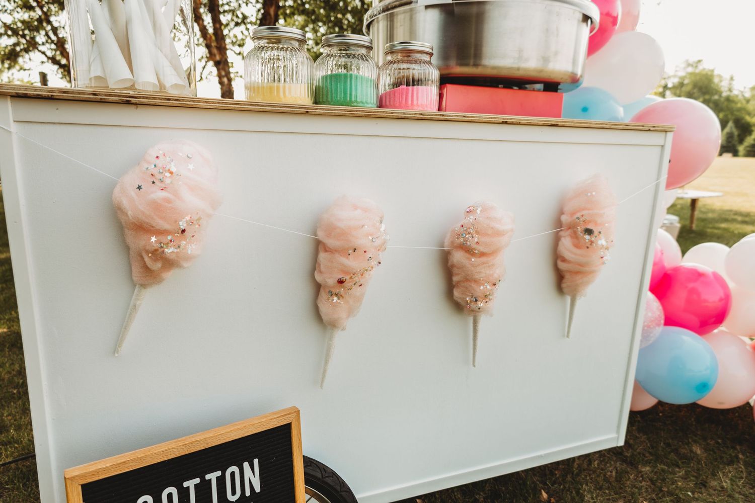 Cotton candy cart decorated with pastel balloons and party decor.