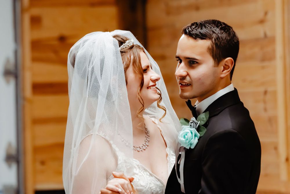 A tender moment between newlyweds during their wedding celebration with rustic wooden backdrop.
