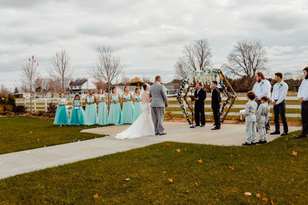 Wedding ceremony setup outdoors with teal decor and white chairs on a grassy field.
