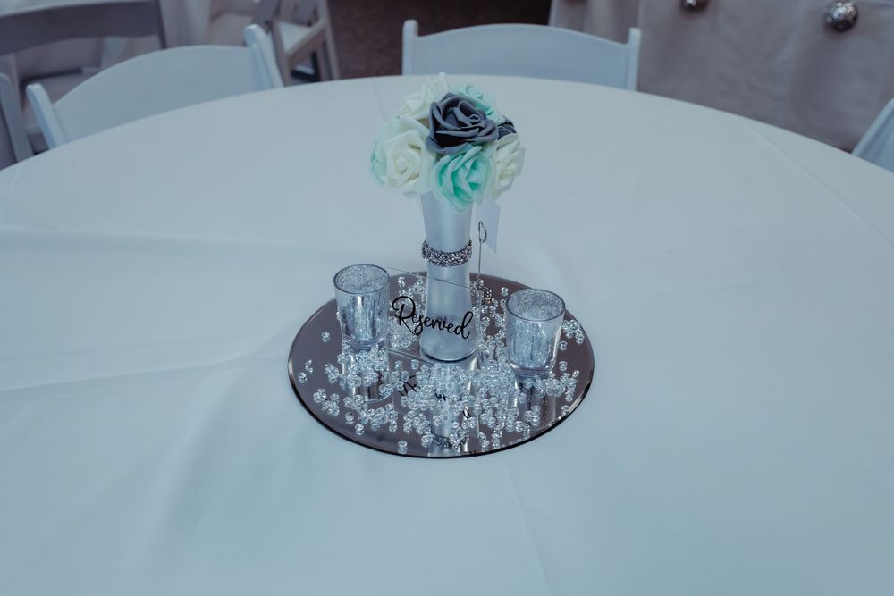 Elegant teal centerpiece with roses on a white tablecloth at a wedding reception.