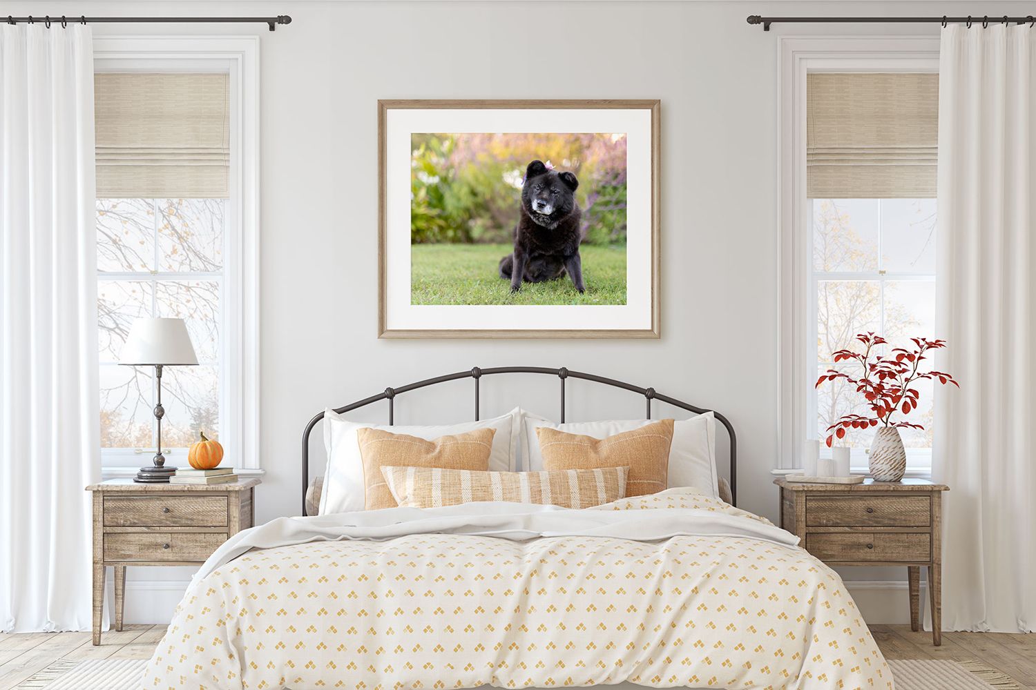 Framed dog portrait displayed above a cozy bedroom with cream bedding and rustic nightstands.