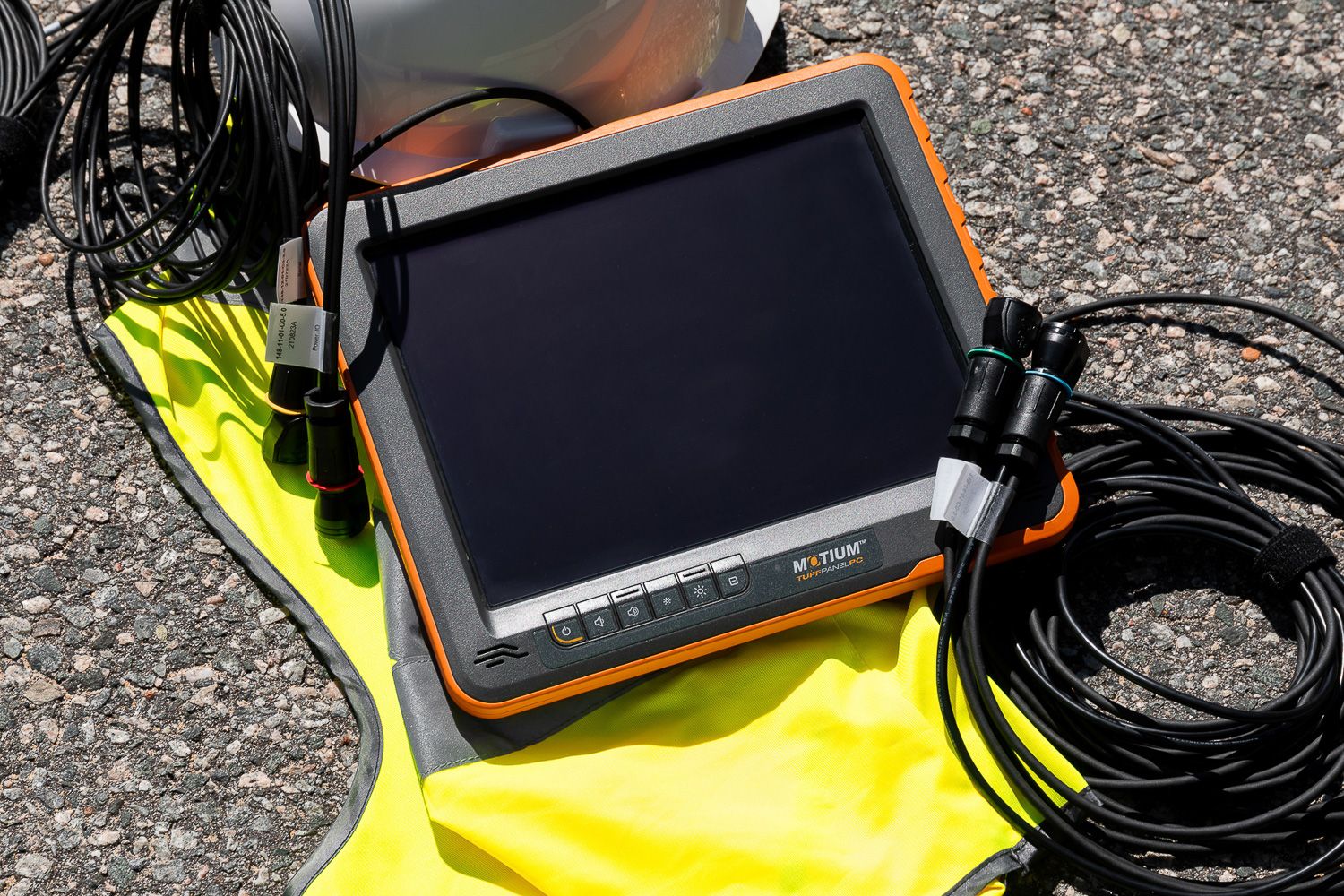 Electronic display monitor with cables on bright yellow surface outdoors.