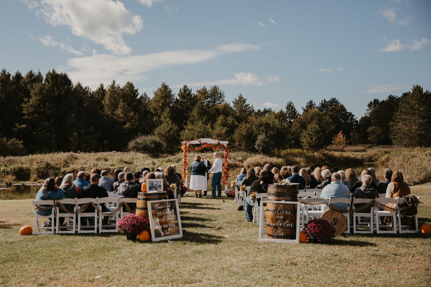 couple stands in front of their family and friends as they proclaim their vows, outdoor ceremony under a trellis of fall leaves and flowers