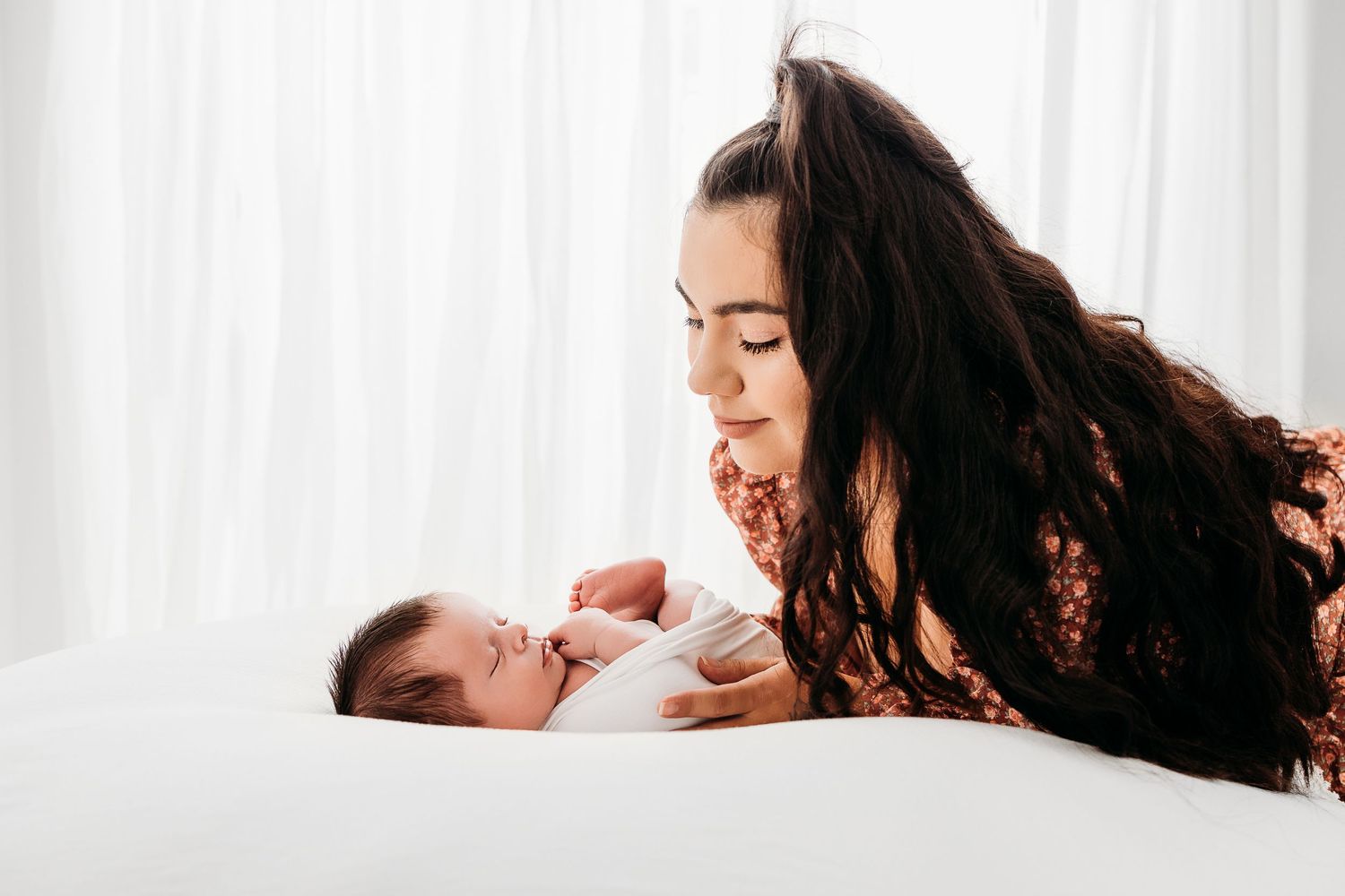 Mom looking down at her newborn baby during her baby's newborn photography session in Santa Fe, NM from Pecos.
