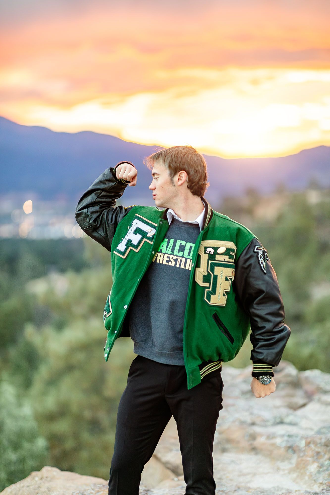 Senior guy flexes one arm in a pose of strength at his senior session at Palmer Park in Colorado Springs.