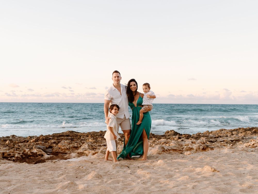 A family photoshoot by Moments With Kell on Oahu in Hawaii with parents and children smiling on the beach
