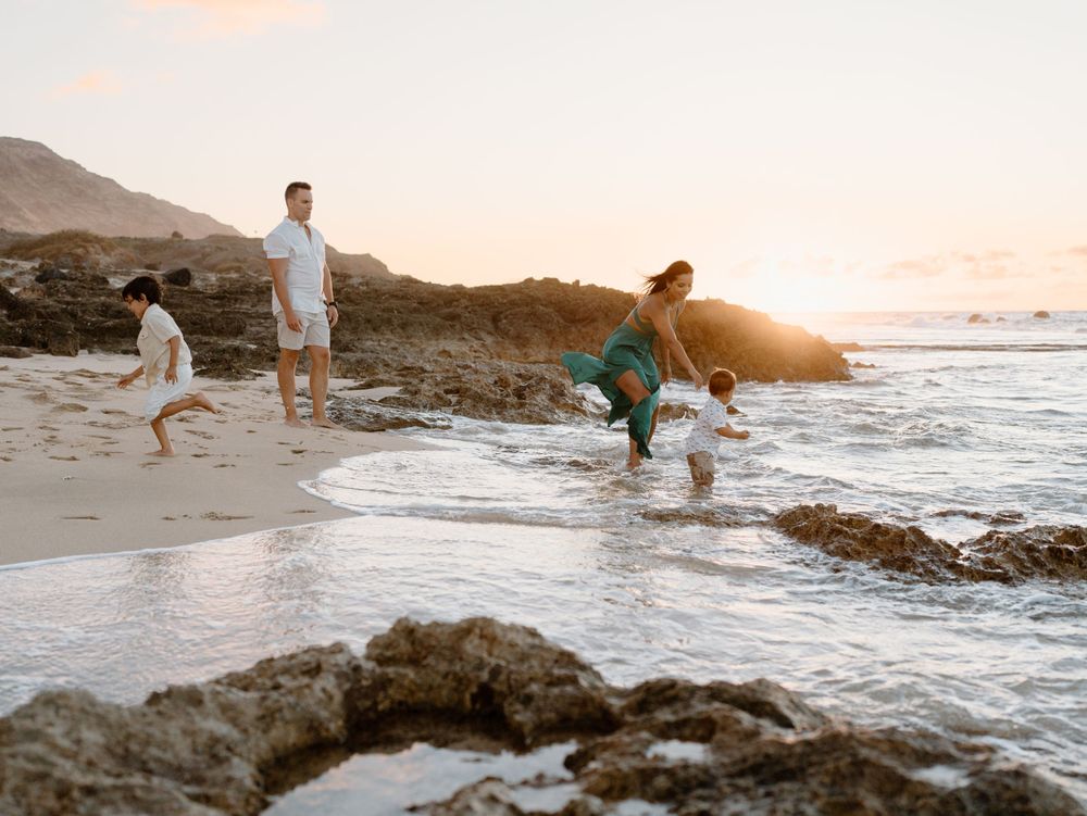 A family photoshoot by Moments With Kell on Oahu in Hawaii with parents and children playing by the ocean
