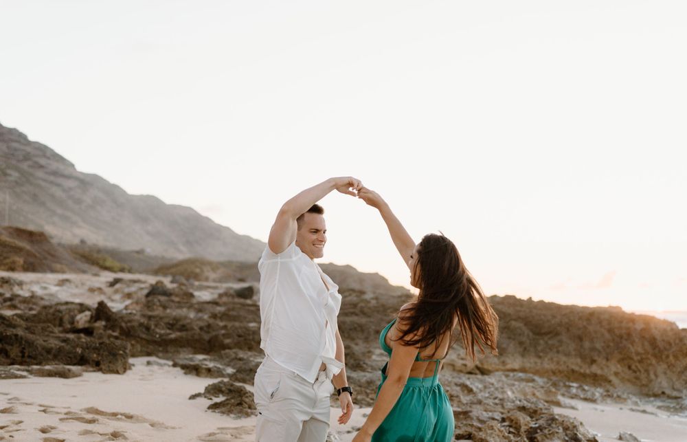 A couples photoshoot by Moments With Kell on Oahu in Hawaii with husband and wife dancing on the beach