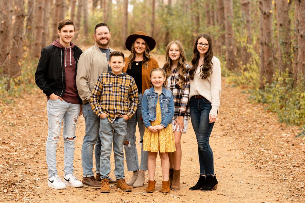 Group portrait of a family standing together on an autumn forest trail.