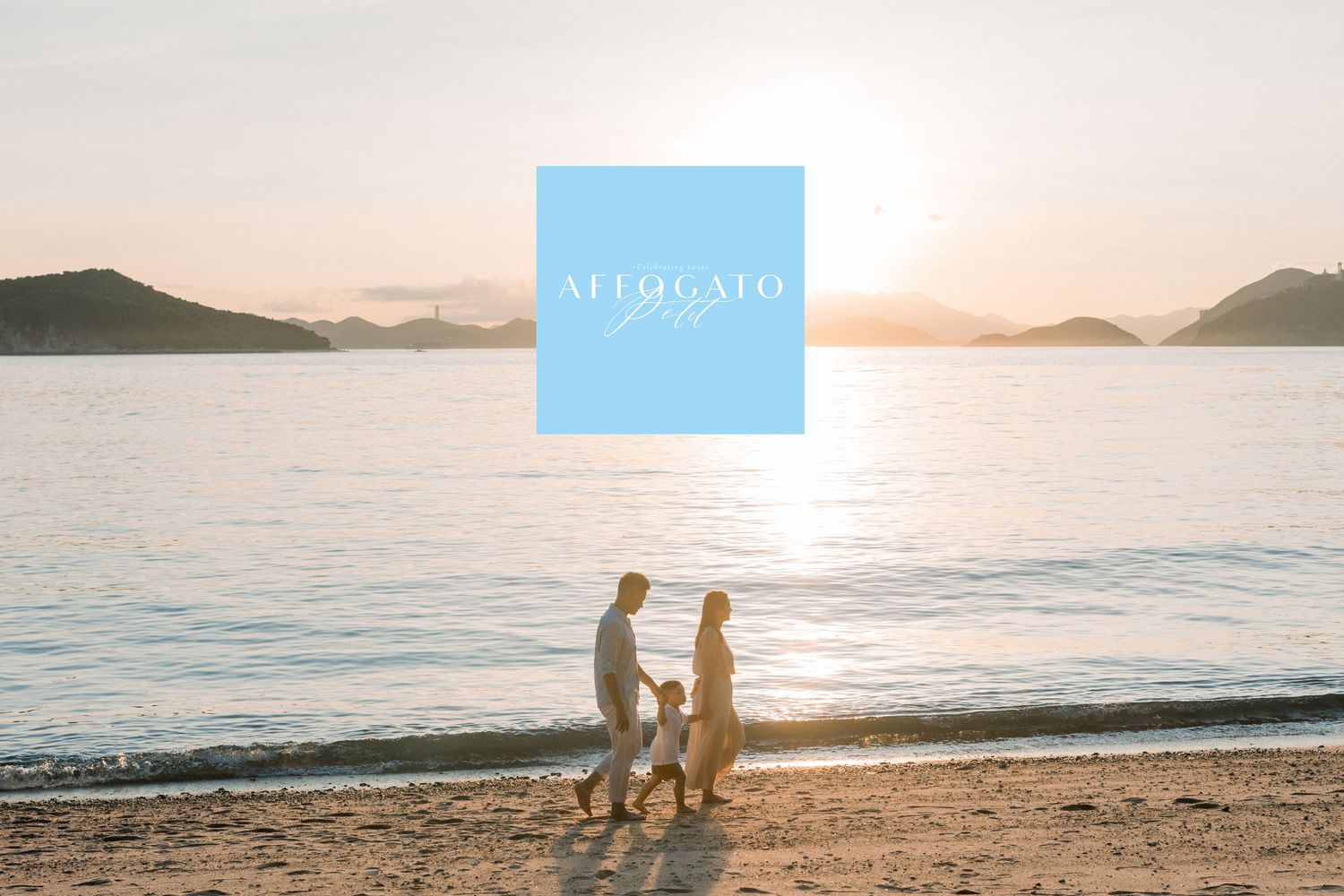 Silhouetted couple walking on beach at sunset with mountains in background.