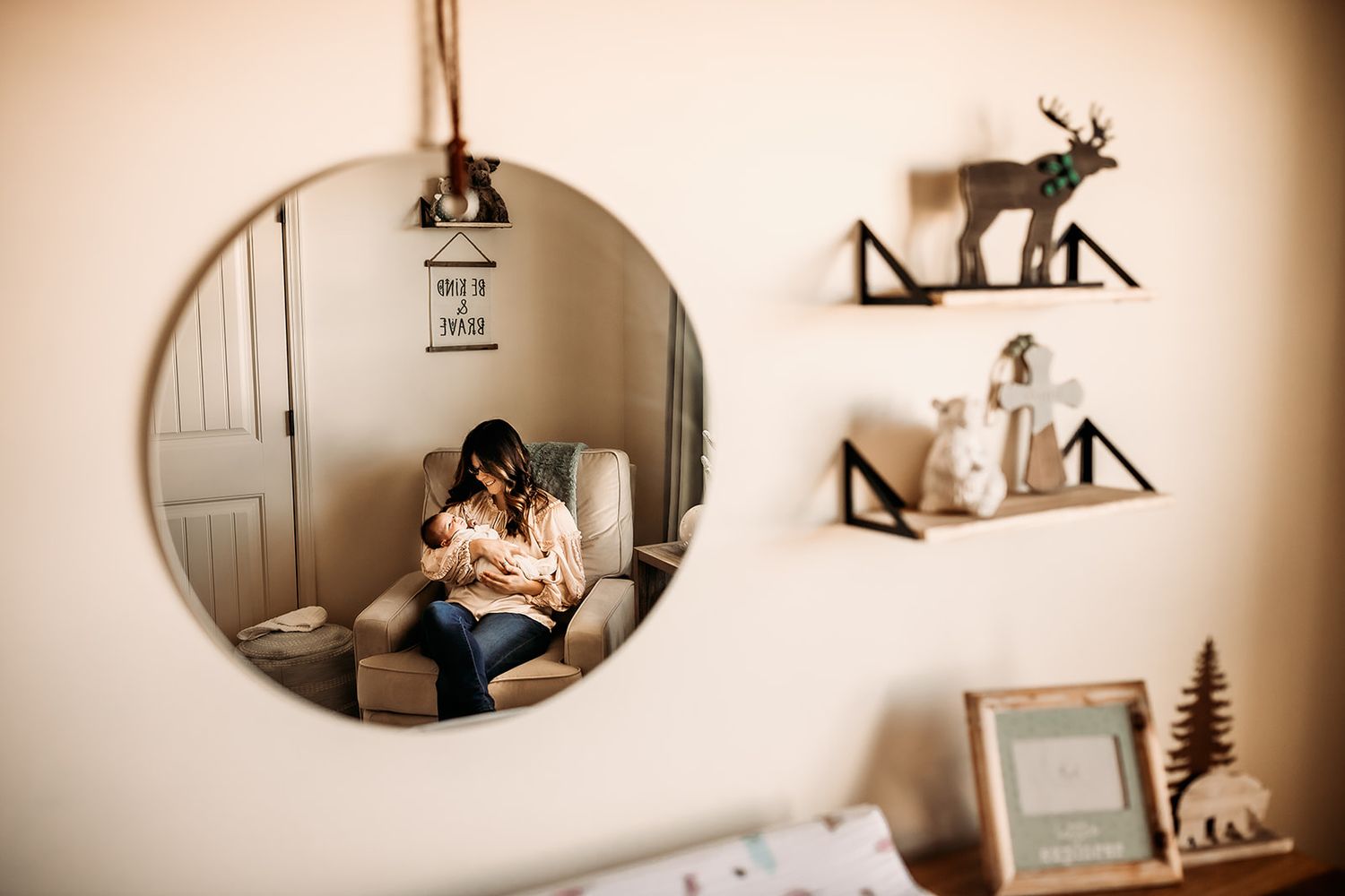 A view through a mirror of a mother rocking her newborn baby boy during newborn photos.