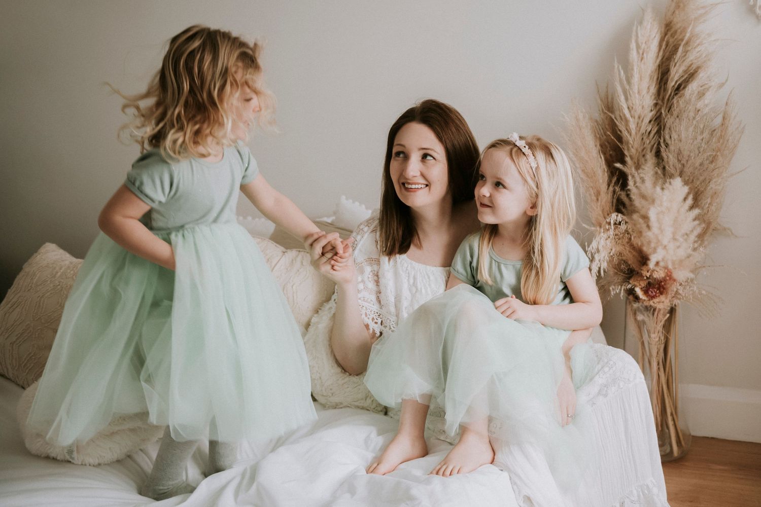 A joyful family moment shared between three people in soft mint and white outfits.