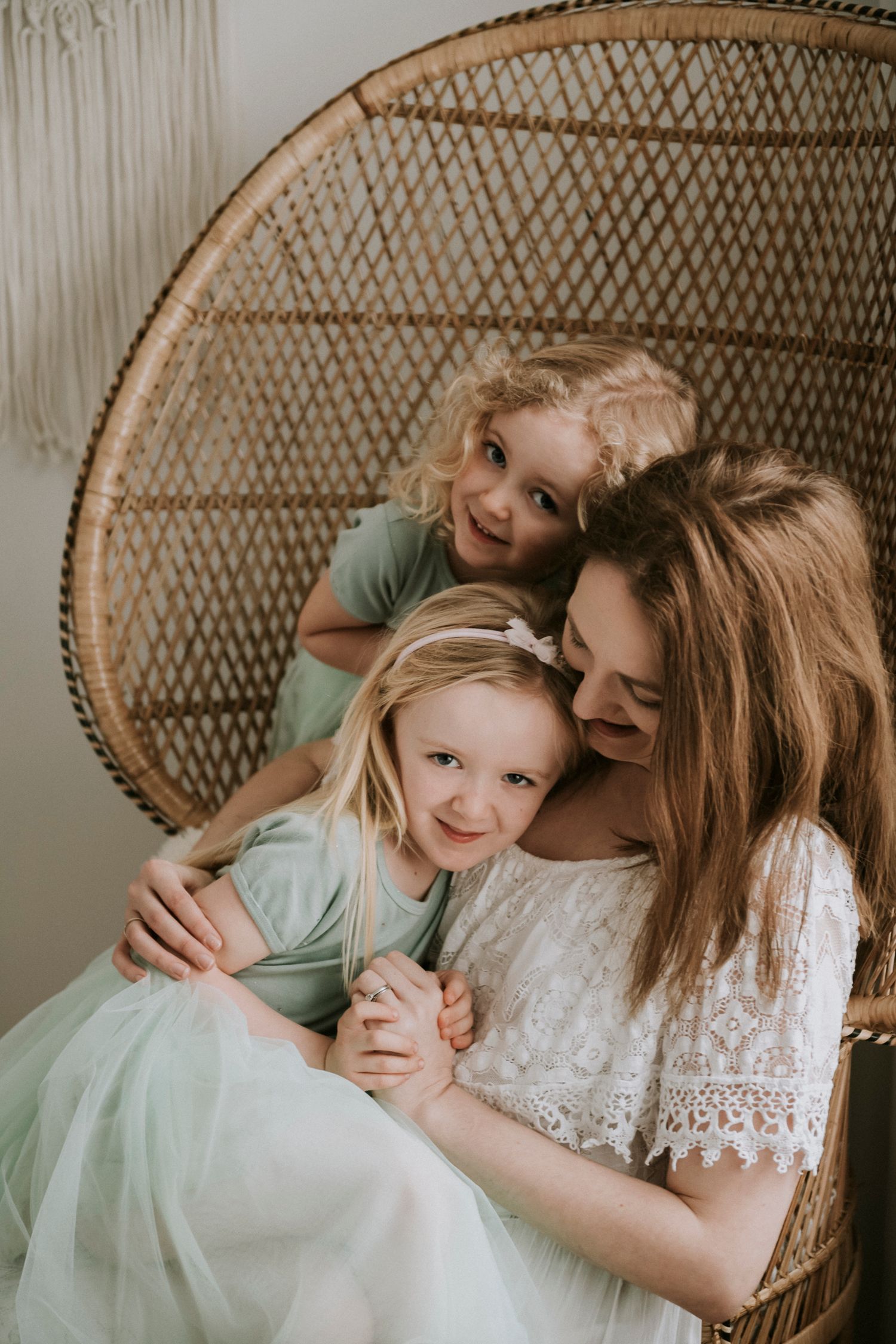 Tender family moment in wicker peacock chair with mint green dresses.