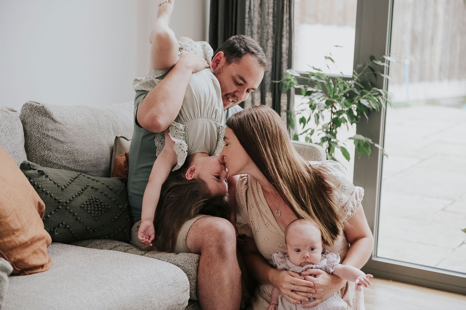 Intimate family portrait session showing joyful interactions on grey sofa.