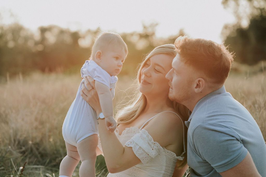 A loving family moment captured at sunset in a golden field.