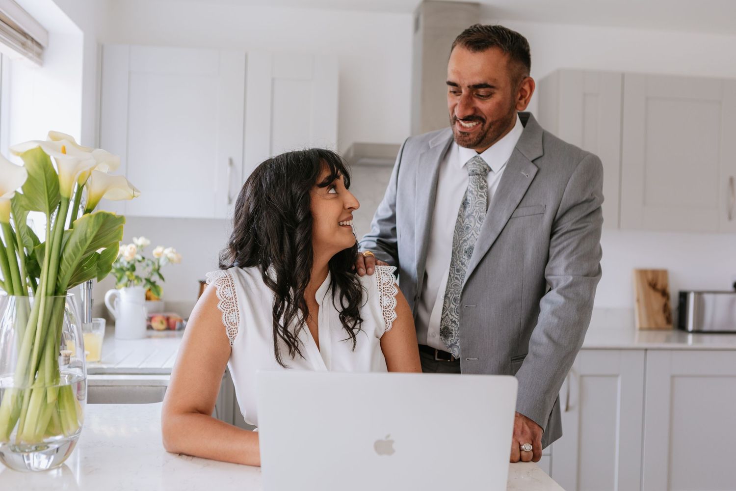 Two professionals collaborating over a laptop in a bright modern kitchen.