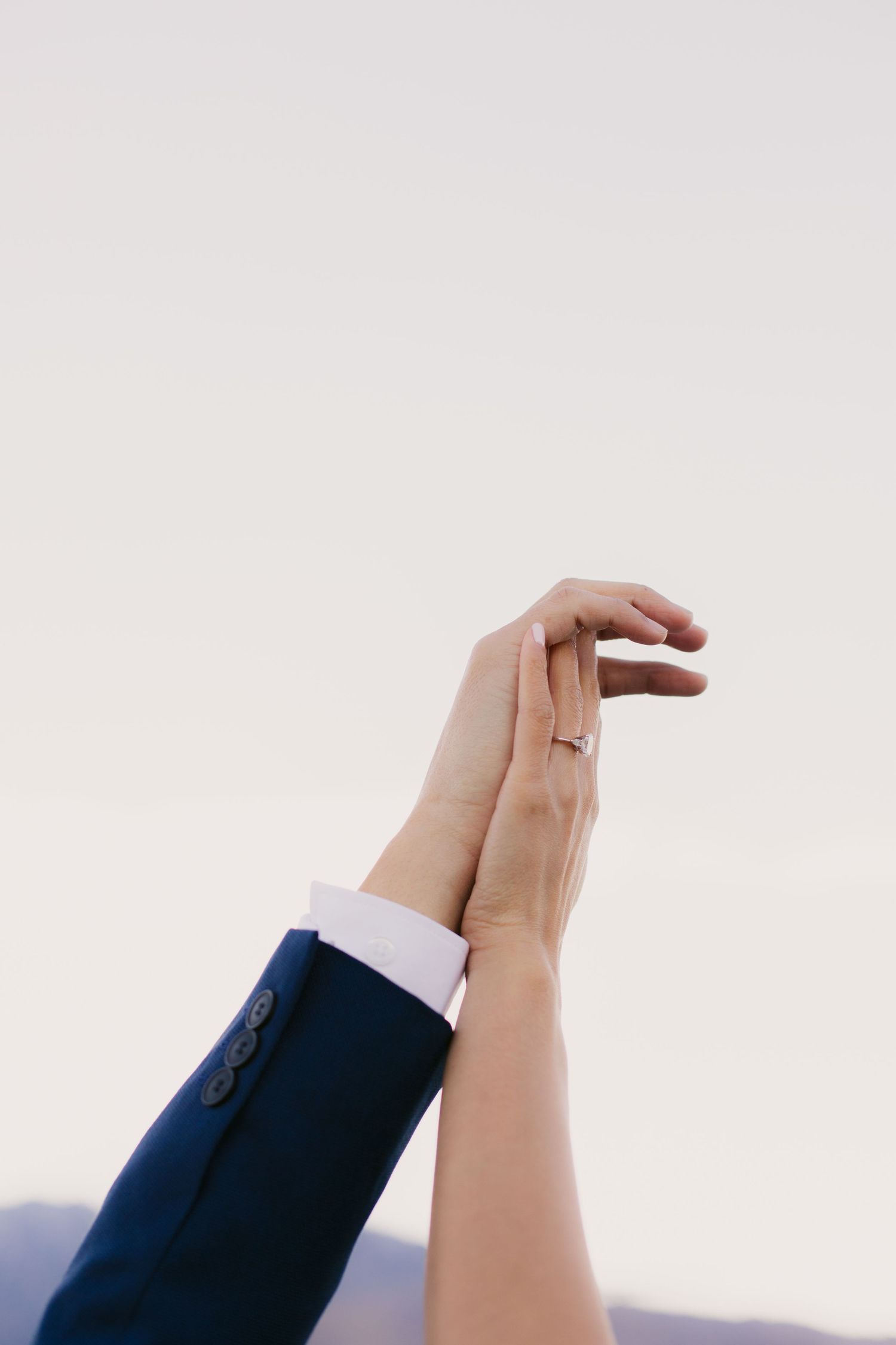 Close-up of hands reaching towards each other against a bright white background.