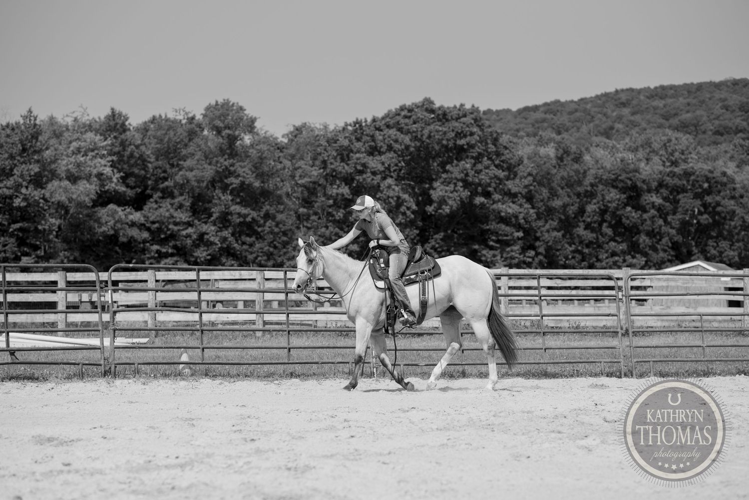 Horse and rider training in outdoor arena in black and white photography.