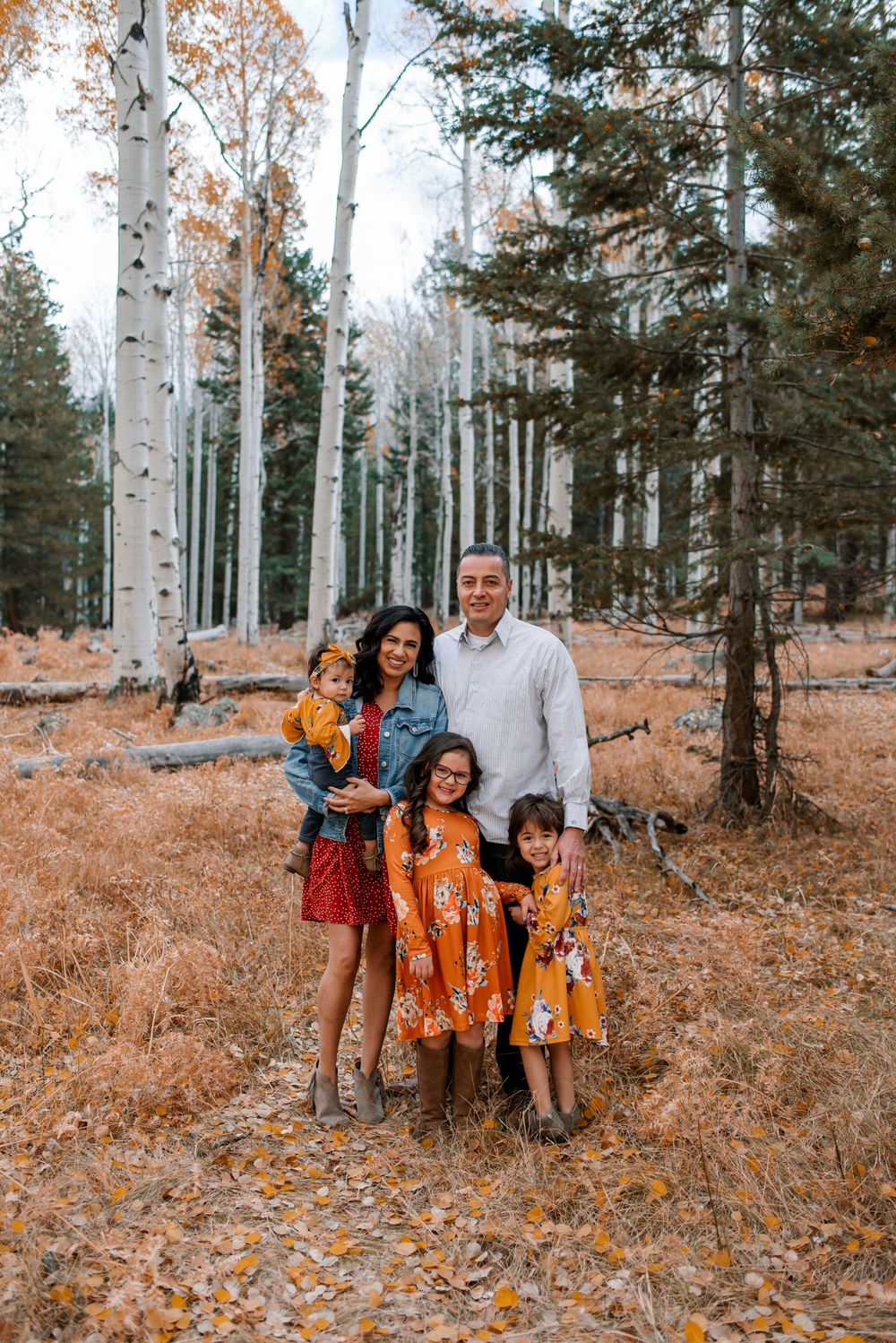 Family portrait in casual attire among white aspen trees during autumn.