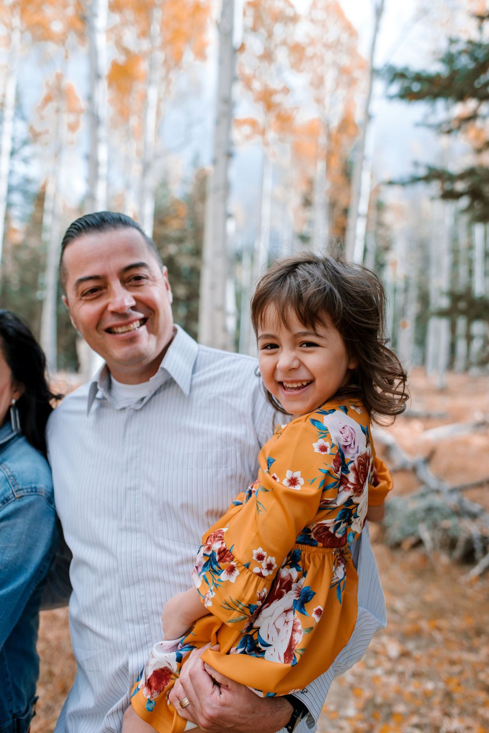 Family shares joyful moments in an autumn aspen forest with golden leaves.