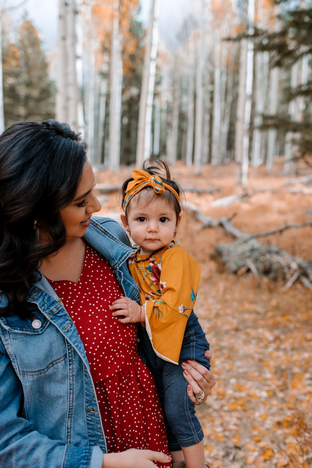 Family members share affectionate moments in a fall-colored aspen grove.