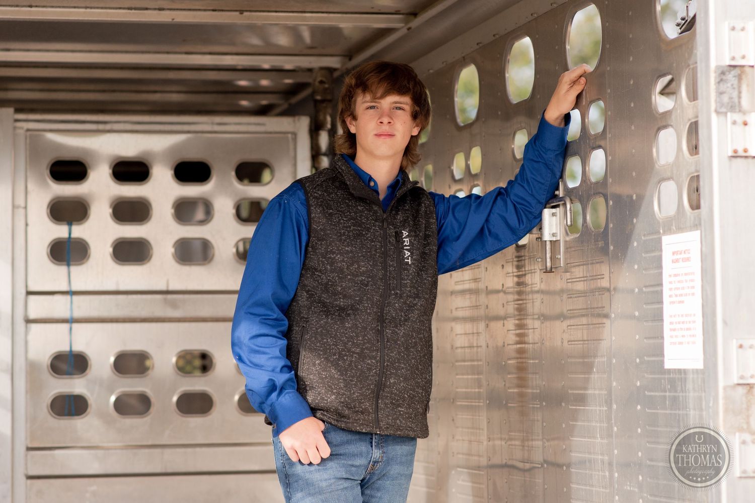 A casual pose inside livestock trailer with distinctive ventilation holes in background.