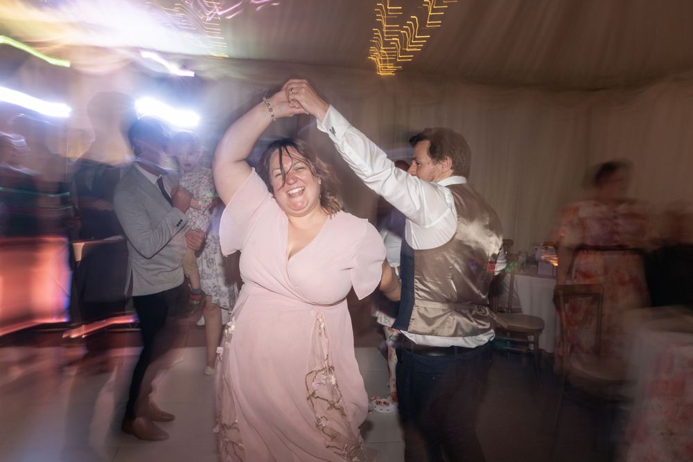 Wedding guests spin and dance under party lights with motion blur effects.