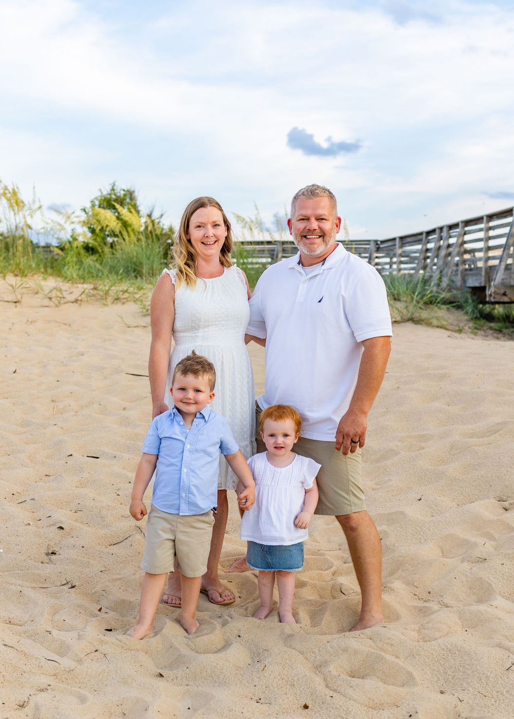 Beach family portrait with everyone standing barefoot in the sand.