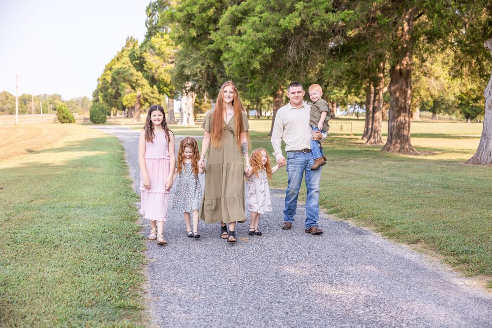 Family walking together on gravel path through park at golden hour.