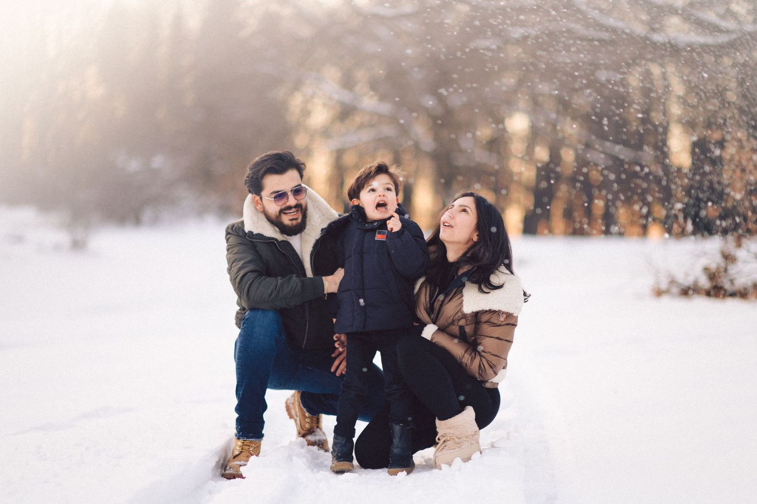 A playful winter family moment captured in golden sunlight.