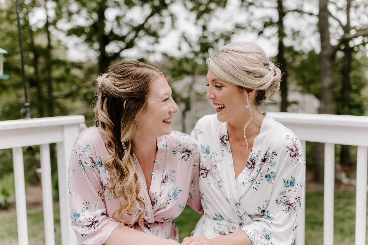 Two people in floral robes share candid moments while sitting outdoors.