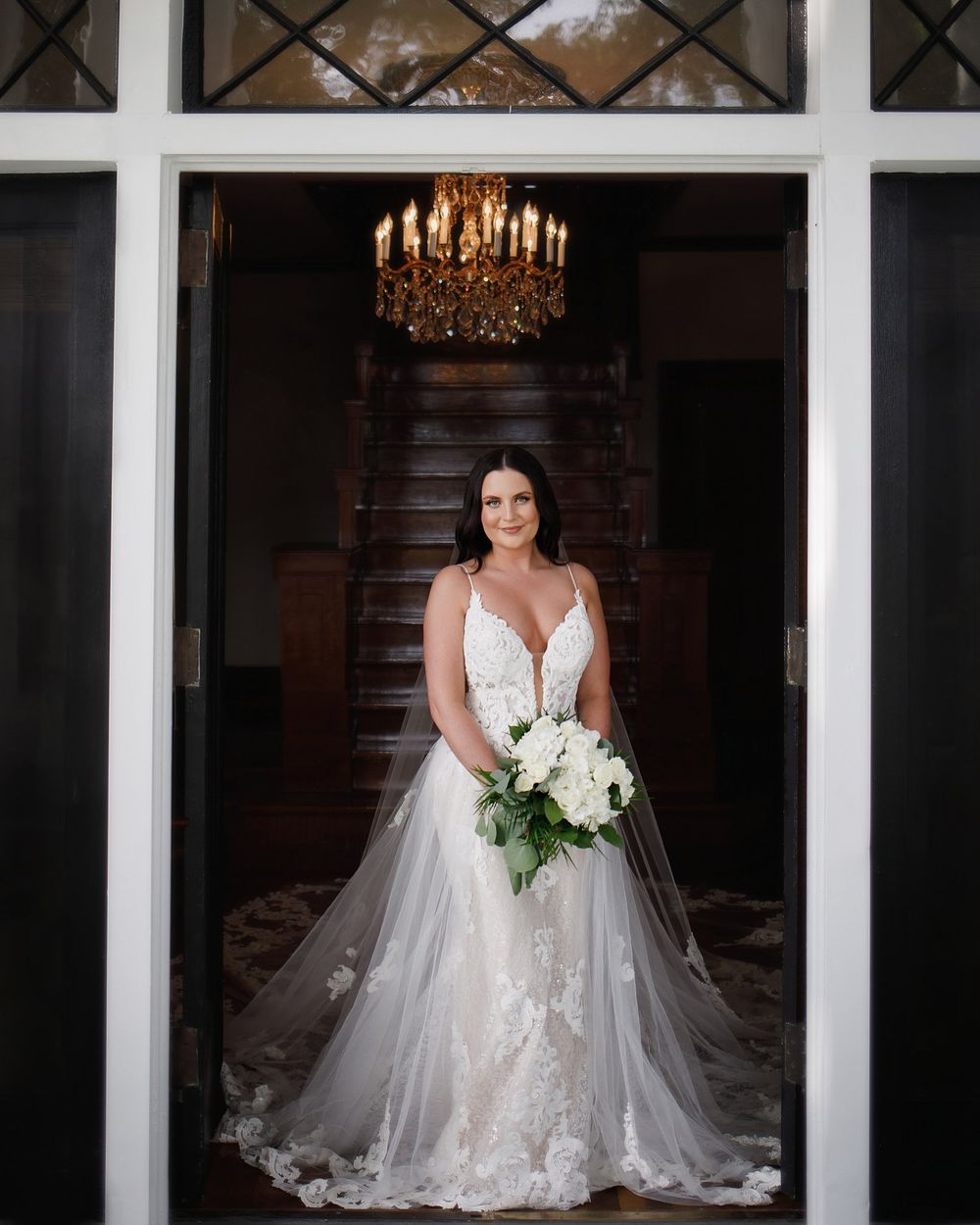 Wedding portraits featuring a stunning white lace bridal gown with cathedral train in an elegant indoor setting.