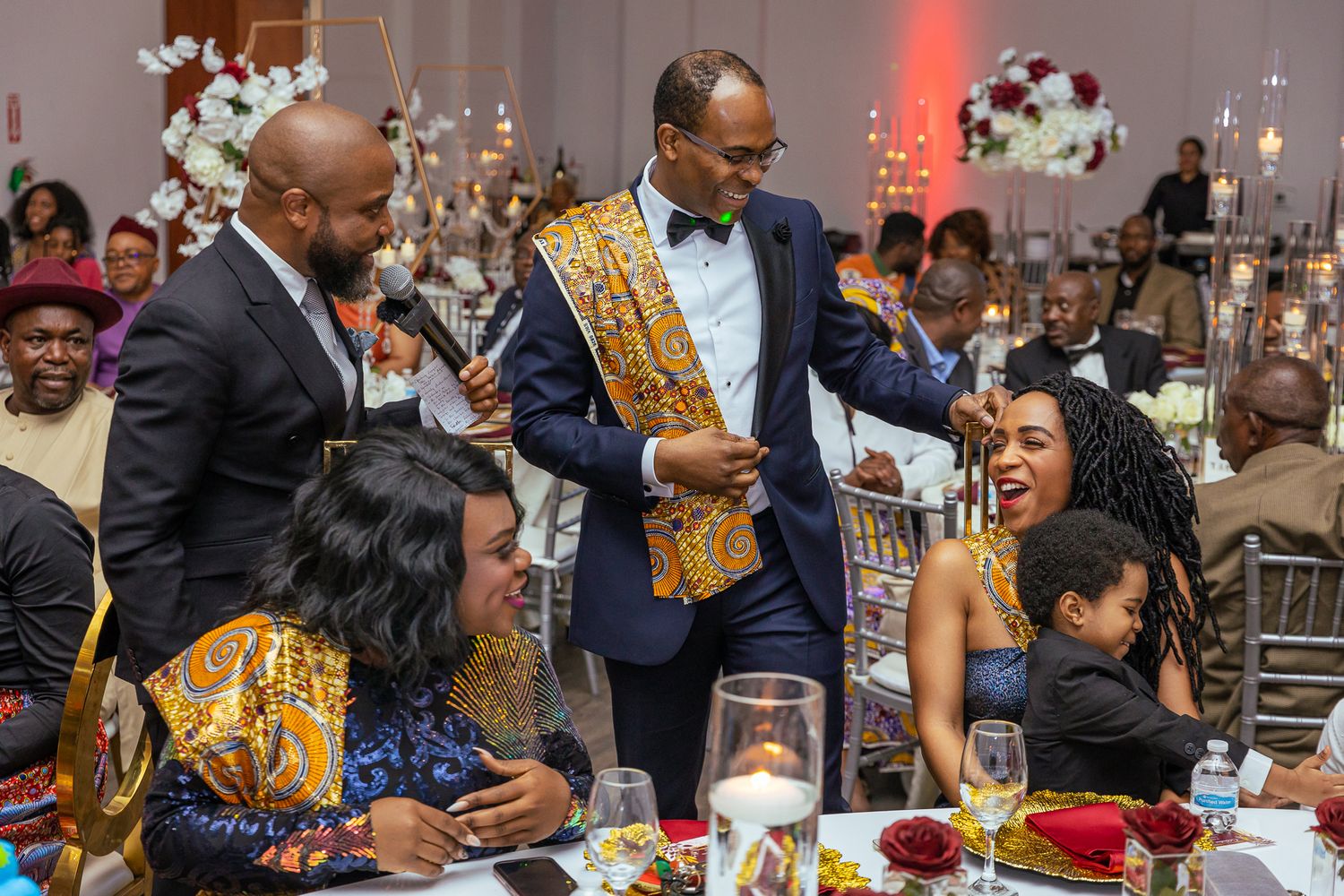 Celebratory scene with people in colorful attire gathered around a table at a festive event.