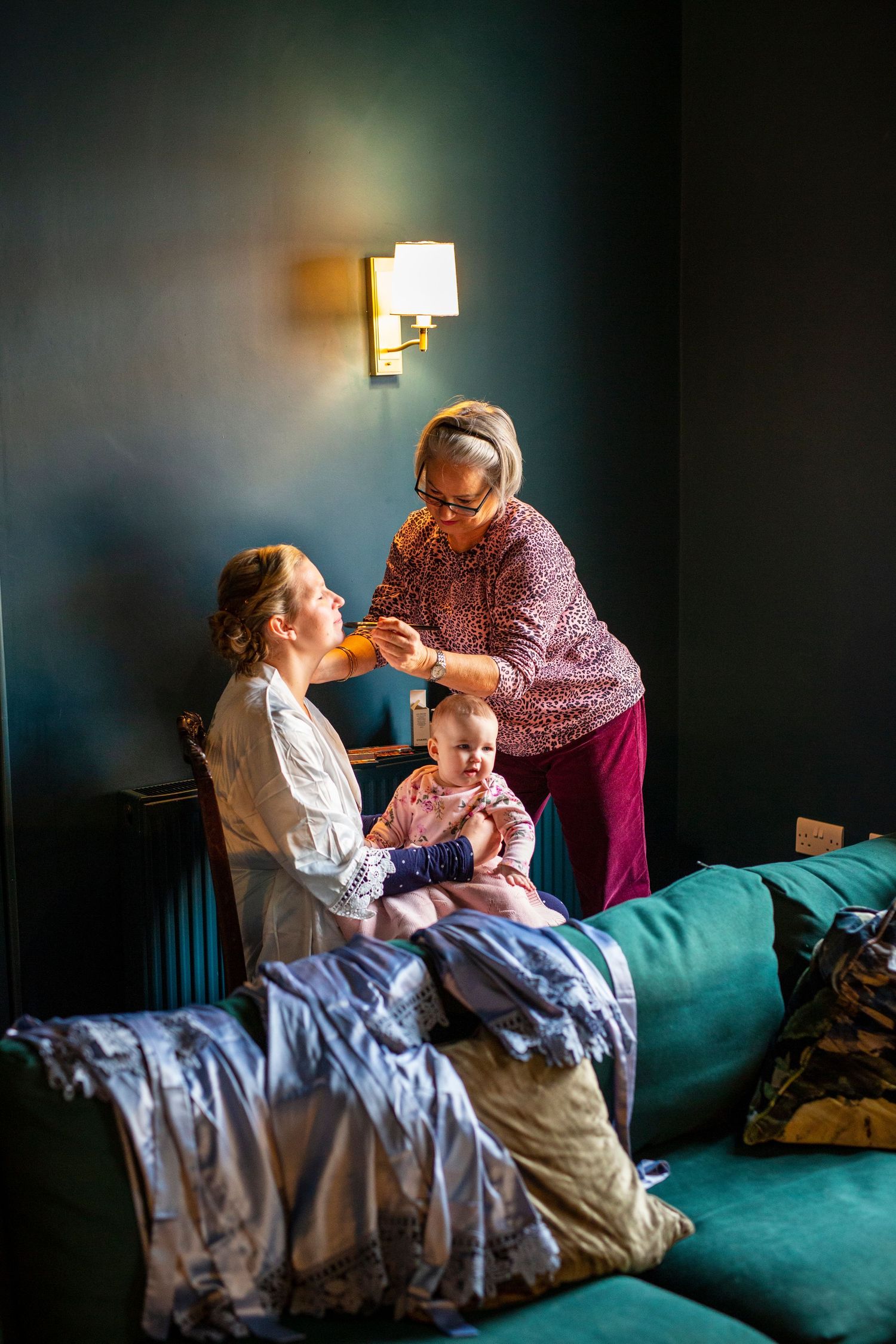 A tender moment captured on a teal couch with soft lighting and a warm atmosphere.