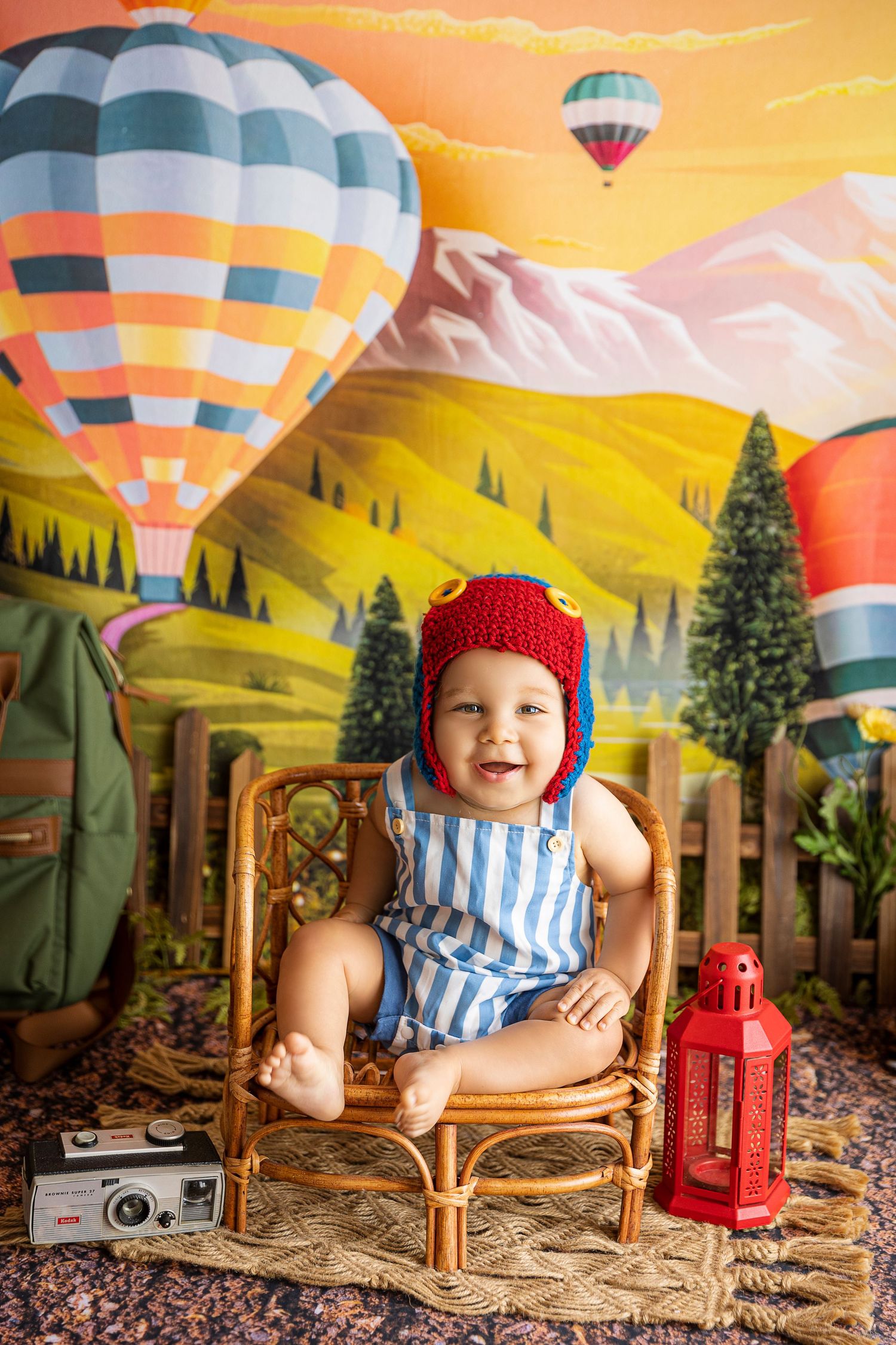 fotografa infantil en ponce bebe sentado en silla de ratan con gorrito tejido puesto tematica de globos aeronautas