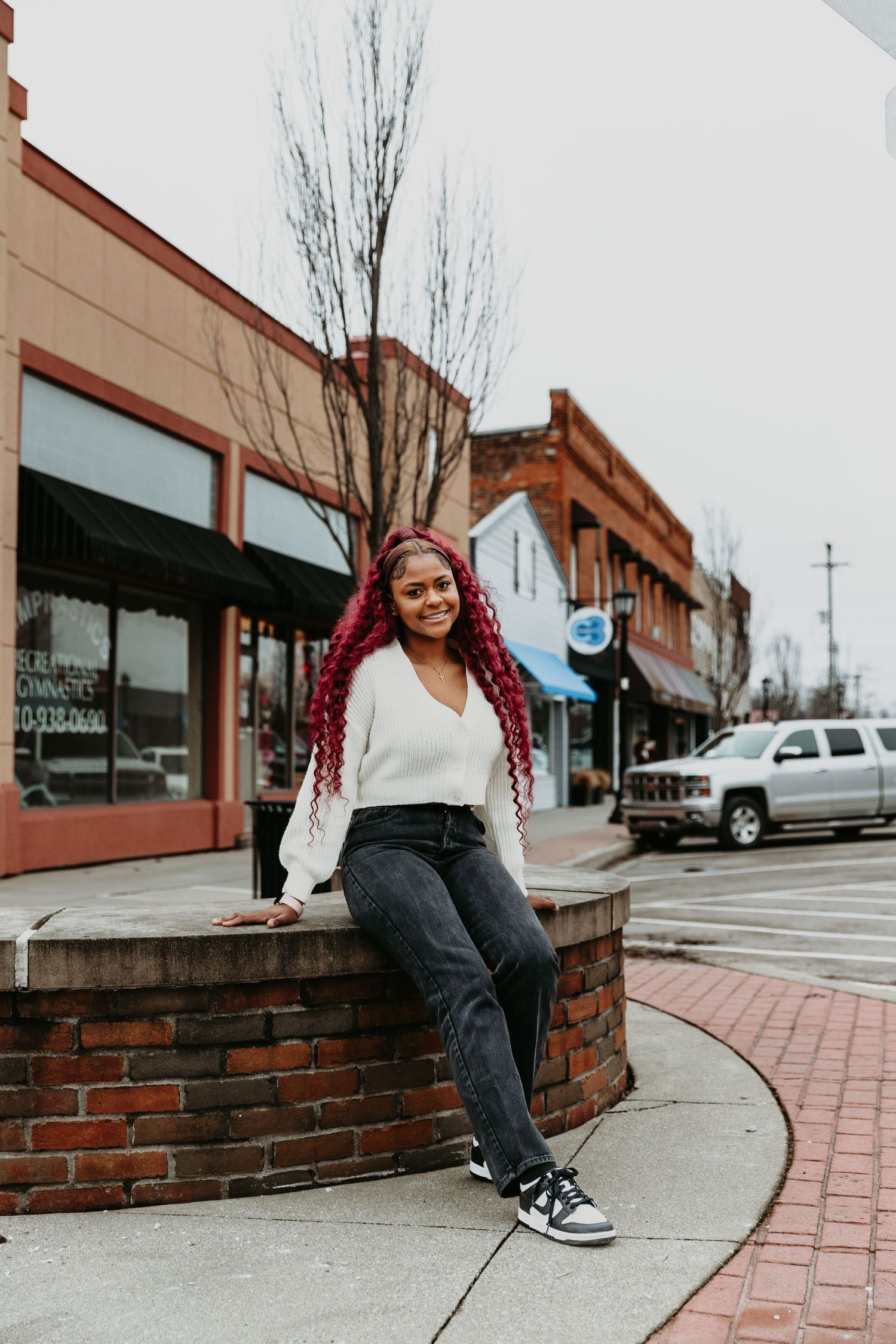 Casual urban photoshoot along brick wall and sidewalk in downtown setting.