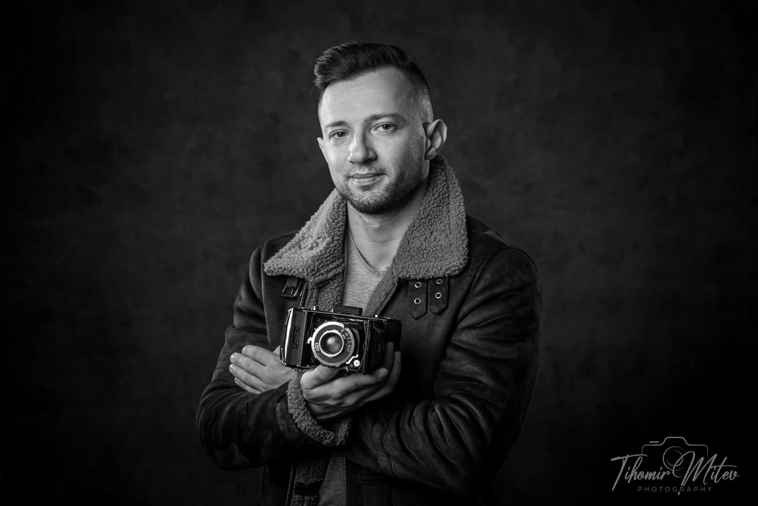 Портретна фотография на мъж с кожено яке и стар фотоапарт