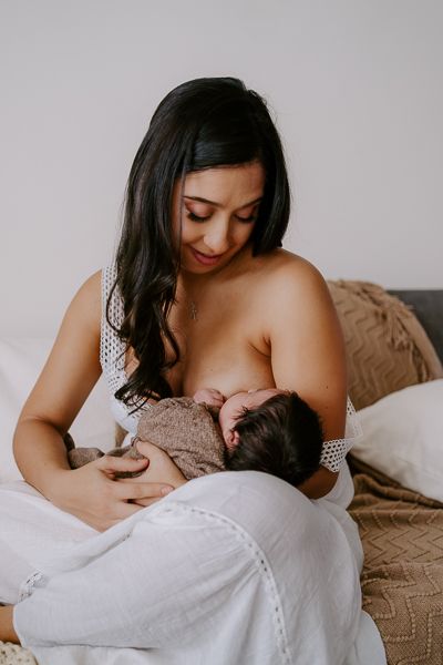 Mutter stillt Baby in der Pause von Neugeborenenshooting