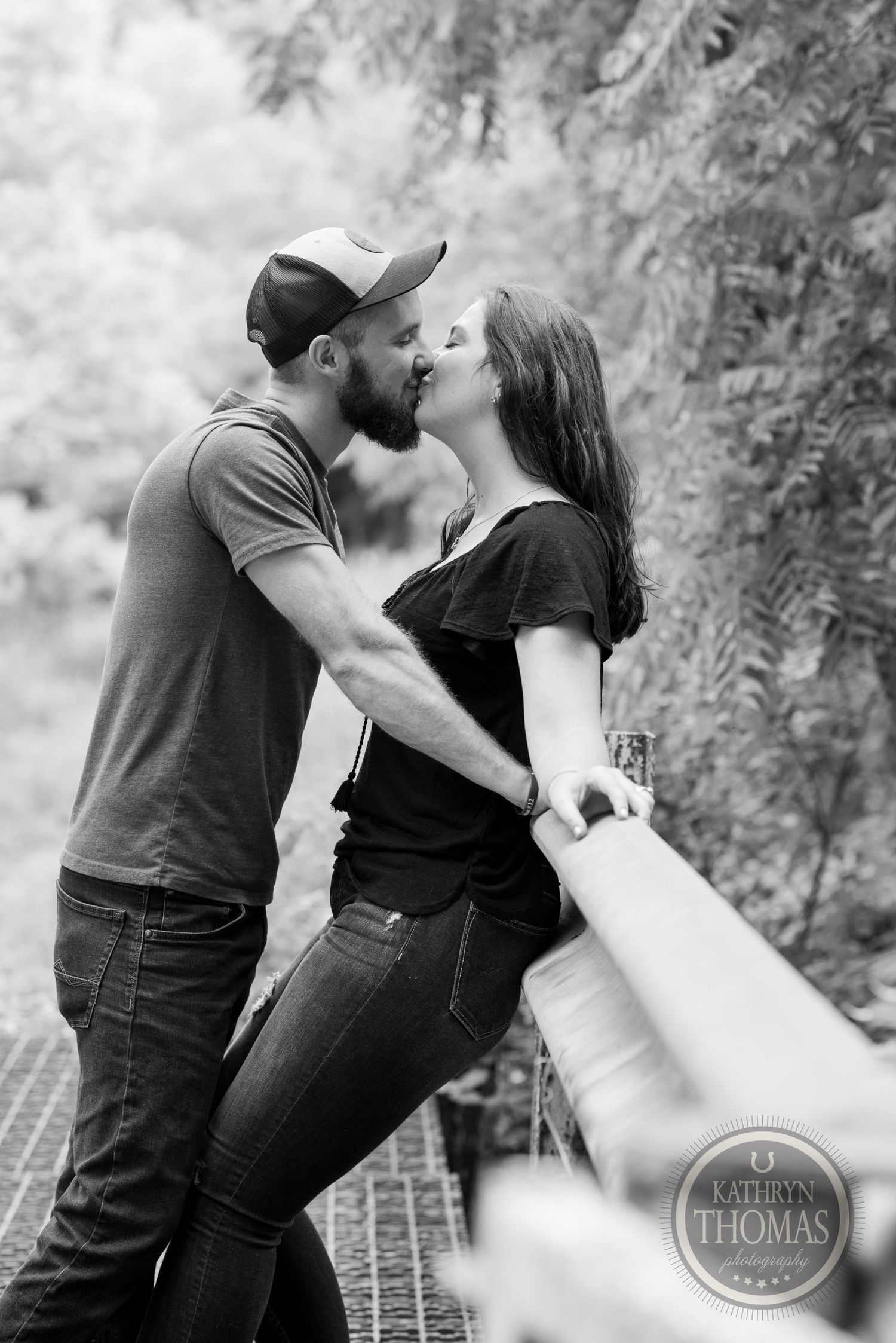 Black and white photo of romantic couple embracing on a wooden walkway.
