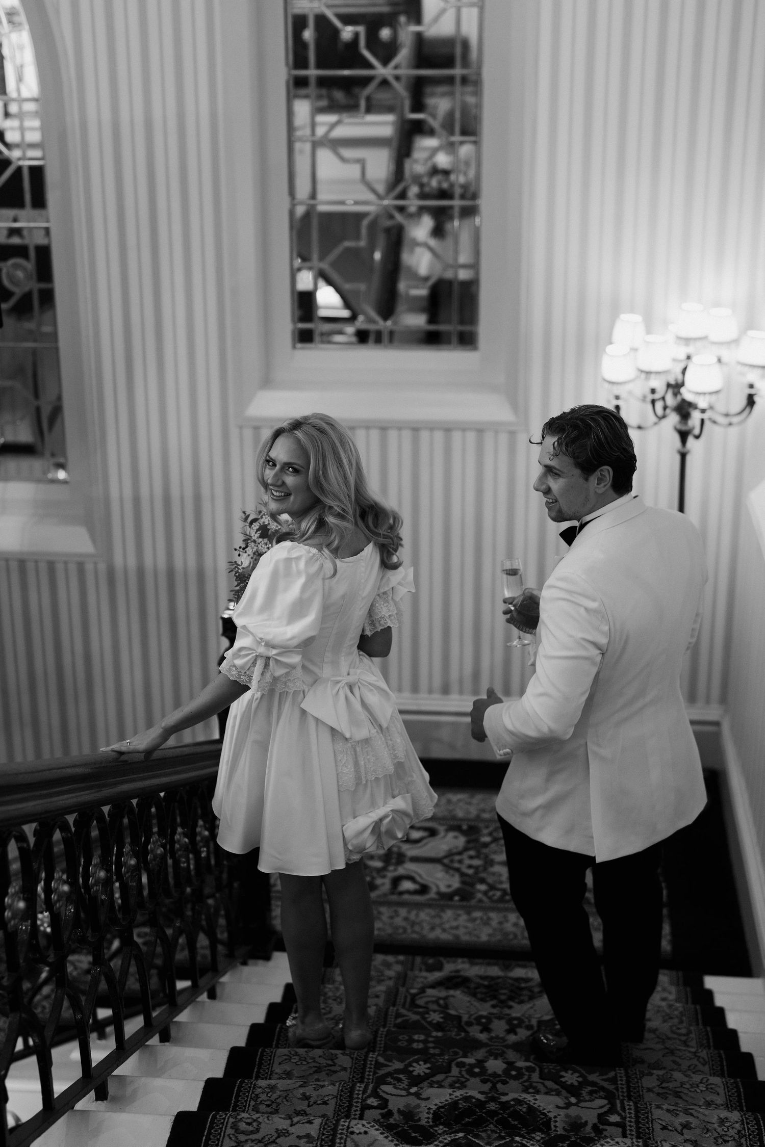 bride looking over her shoulder as she descends stairs with groom at the Randolph hotel in oxford