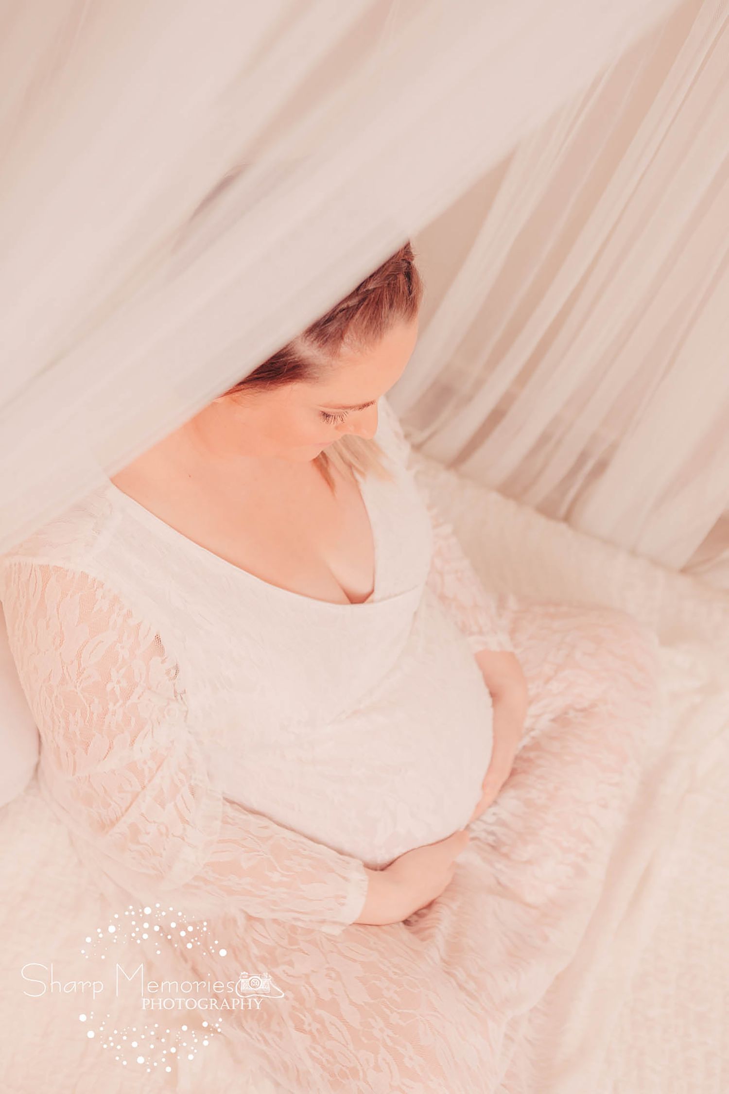Soft and dreamy maternity photo through white sheer fabric.