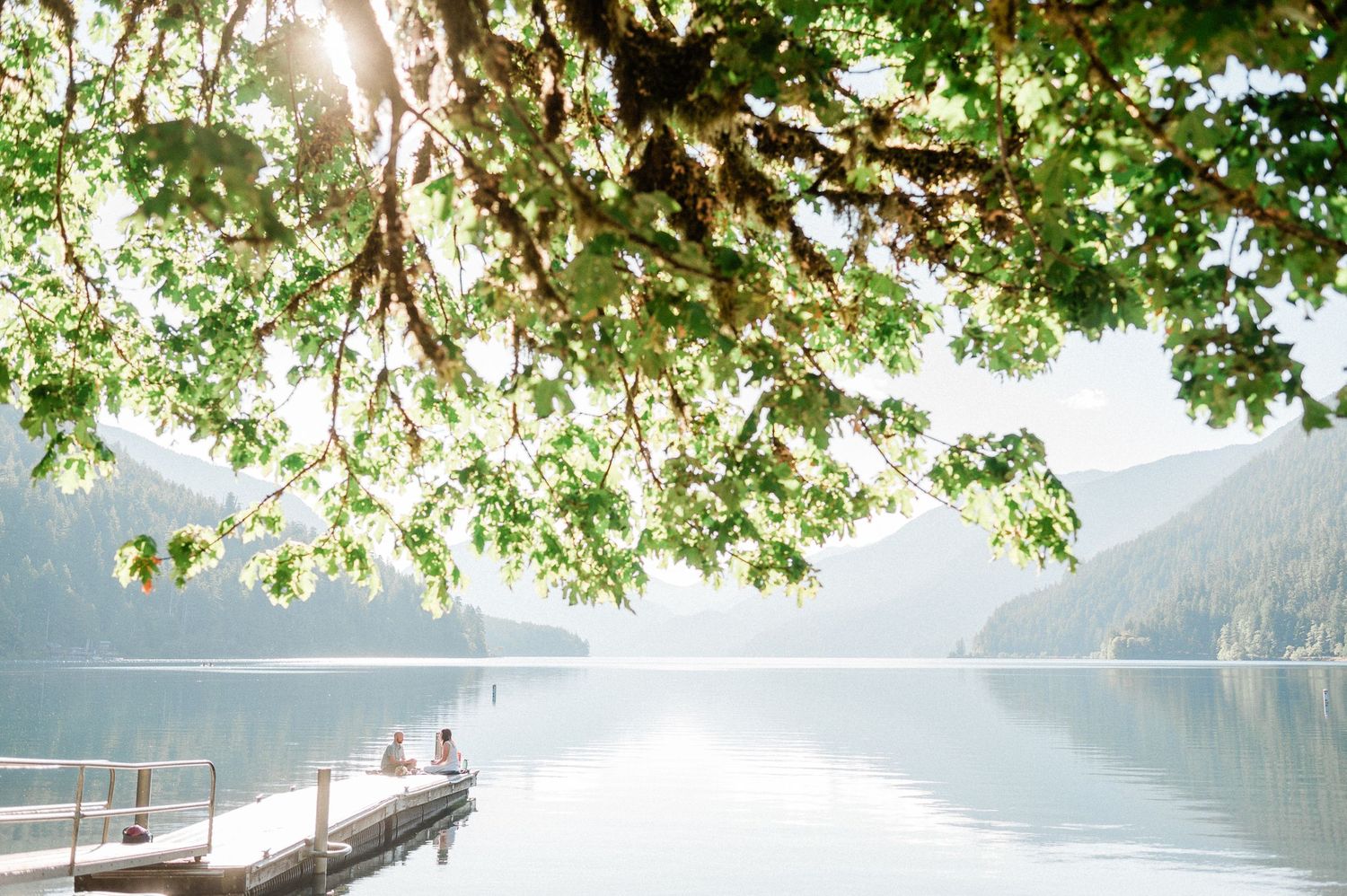 couple sitting at the end of dock at Lake Crescent