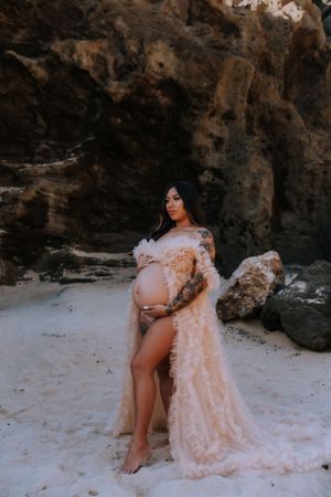 Maternity photos featuring a flowing peach dress against dramatic coastal scenery.