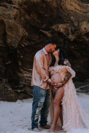 A couple shares tender moments during their beachside maternity photography session.
