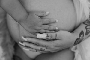 Monochrome maternity photo showing gentle hands resting on belly.