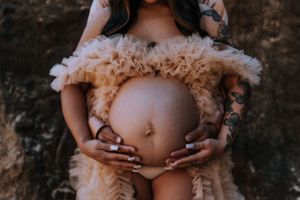 Close-up of a pregnant belly with hands gently placed on top.