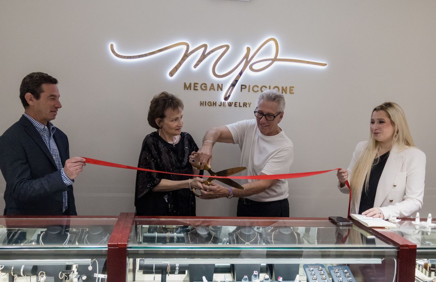Ribbon cutting ceremony at MP store with illuminated logo sign on wall.